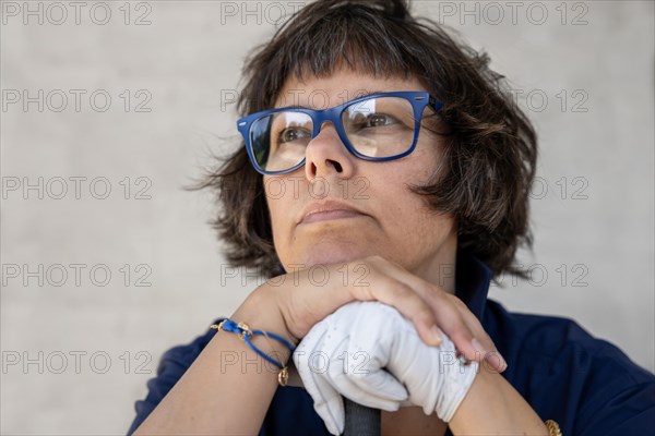 Female Golfer with Eyeglasses and a Glove Leaning on Her Golf Club and Looking Away in a Sunny Day in Switzerland