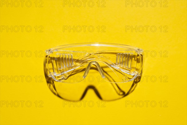 Top view of plastic safety goggles against a yellow background