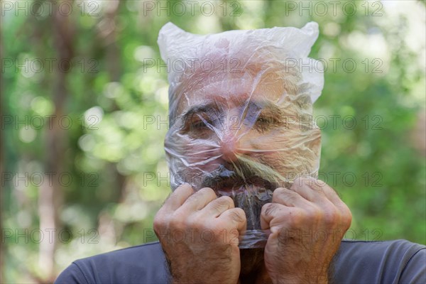 Man with a plastic bag on his head drowning in the countryside