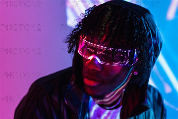 Studio portrait with purple and blue neon lights of a cool futuristic man with augmented reality goggles