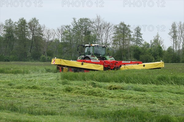 Farmer mowing meadow with three mowers