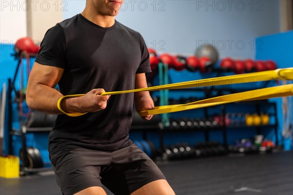 Unrecognizable sportive man with an arm amputated training in a gym using a rubber band