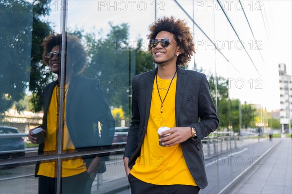 Casual and stylish african american man drinking take away coffee walking along the city