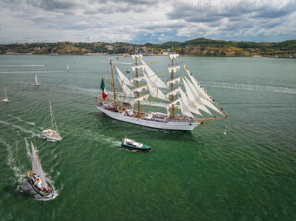 Aerial drone view of tall ships with sails sailing in Tagus river towards the Atlantic ocean in Lisbon