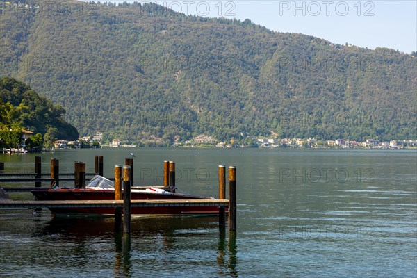 Elegant Motorboat in a Port on Lake Lugano and Mountain Range in a Sunny Summer Day in Lugano