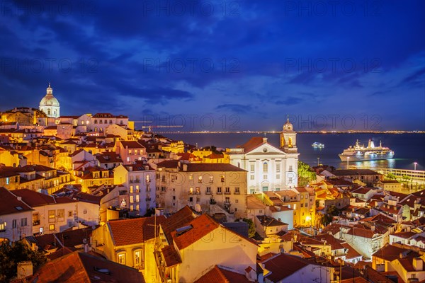 View of Lisbon famous view from Miradouro de Santa Luzia tourist viewpoint over Alfama old city district at night with cruise liner. Lisbon