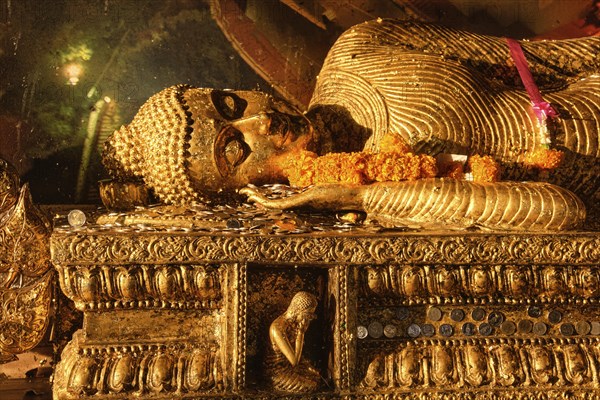 Statue of reclining Buddha covered with golden leaves