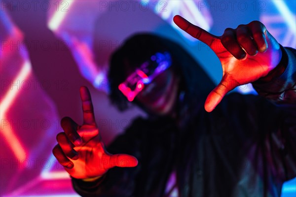 Studio portrait with purple and blue neon lights of a futuristic man picturing the future gesturing with hands