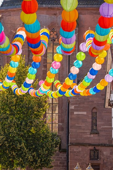 Colourful lanterns hanging in alleyway alley between half-timbered houses