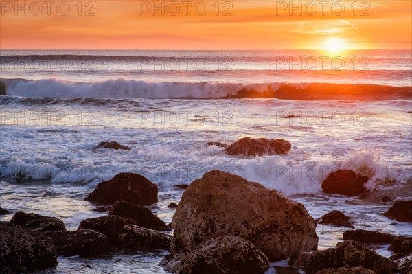 Atlantic ocean sunset with waves and rocks at Costa da Caparica
