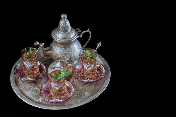 Tray with Moorish tea with mint and silver pitcher and sugar bowl isolated on black background and copy space