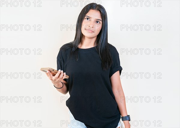 Pensive latin girl holding smart phone on white background. Thoughtful attractive girl holding phone isolated