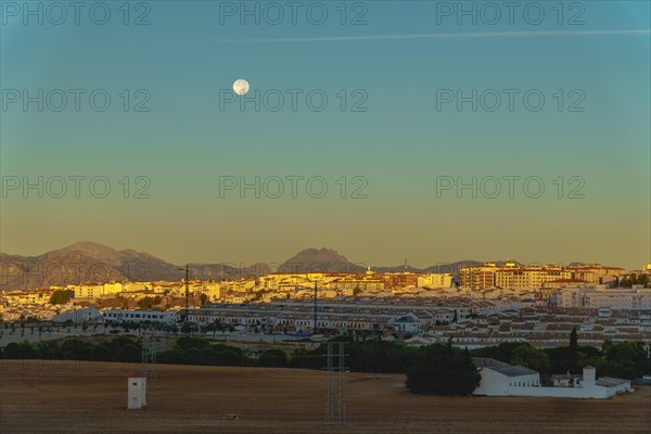 Sunrise cityscape with reddish and blue tones with a full moon in the sky in ronda