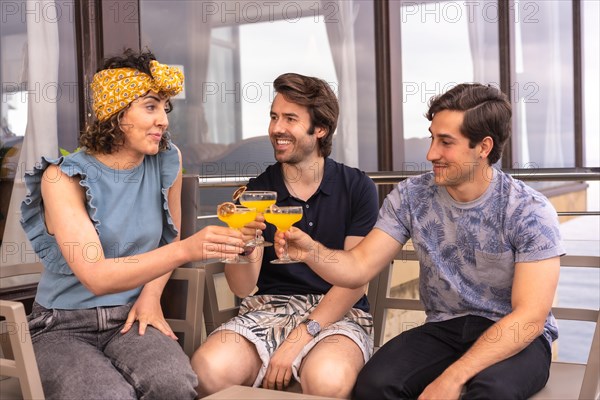 Casual friends with summer clothes toasting on an outdoor terrace