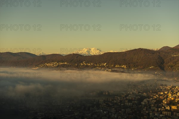 Snow-capped Mountain Peak Monte Rosa Above Cloudscape and Lake Lugano with Sunlight and Clear Sky in City of Lugano