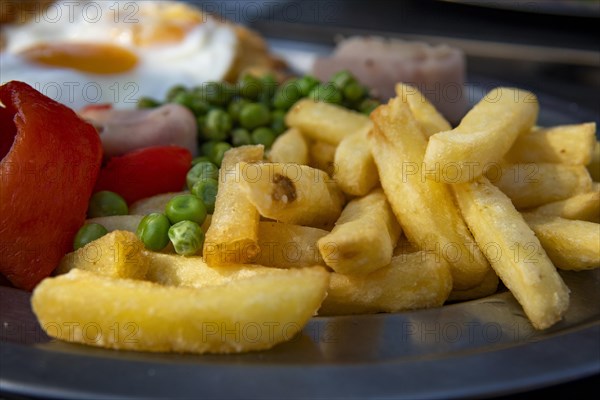 Milanese with fries fried egg peas ham and bell pepper