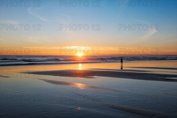 Atlantic ocean sunset with photographer silhouette taking images of surging waves at Fonte da Telha beach