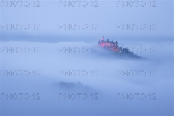 Hohenzollern Castle with Christmas lights in the fog from the Zeller Horn