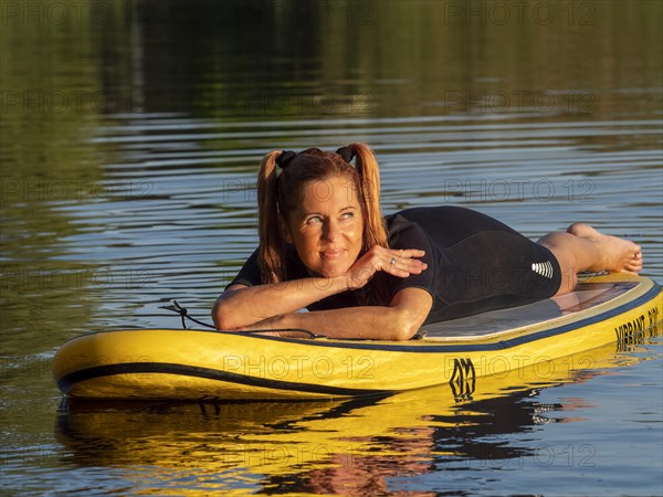 Woman lying relaxed on standup paddle board in lake