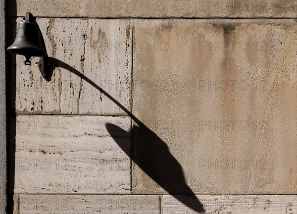 Old Door Bell with Shadow on a Stone Wall with Sunlight in Switzerland