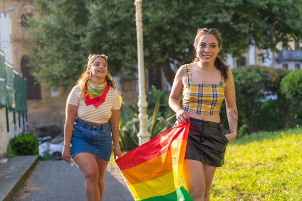 A closeup shot of two young Caucasian females holding LGBT pride flag outdoors