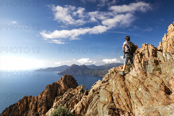 A hiker stands on a rock in the Calanche