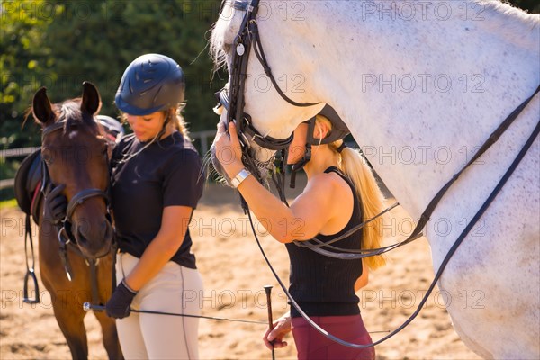 Two young Caucasian girl riders with their white and brown horses on a horse riding