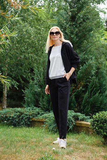 Active woman in hoodie and fleece trousers standing on backyard