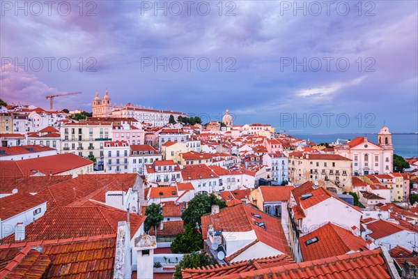 View of Lisbon famous view from Miradouro de Santa Luzia tourist viewpoint over Alfama old city district on sunset with dramatic overcast sky. Lisbon