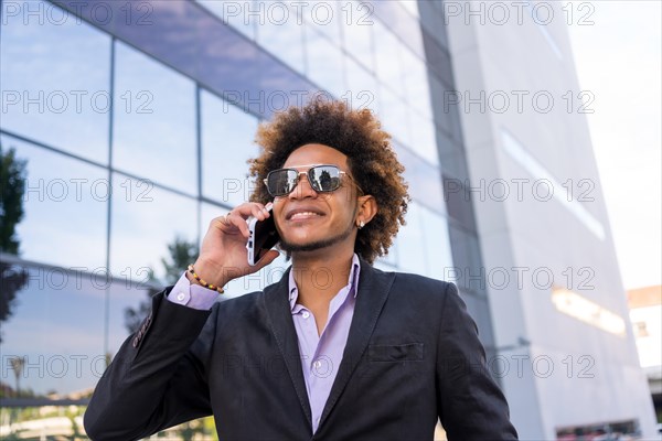 Low angle view of a elegant african american financial advisor receiving a call in the street