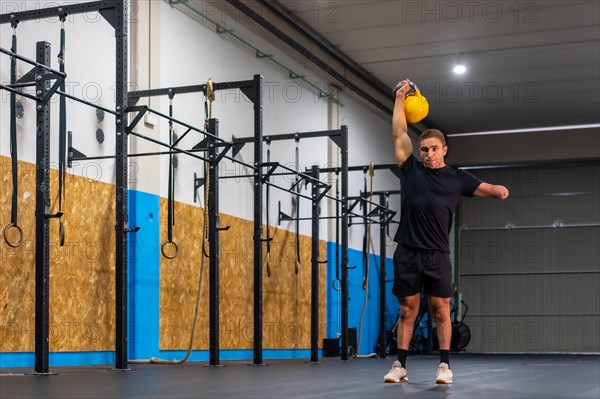 Portrait with copy space of a disabled sportive man lifting a kettlebell in a cross training gym