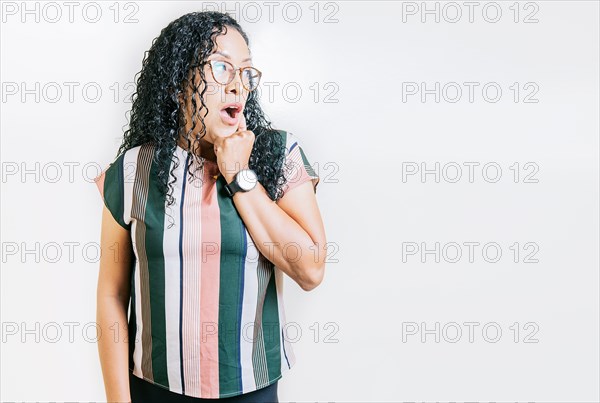 Amazed latin woman with hand on chin looking at copy space. Surprised girl looking at a promo. Amazed people with hand on chin looking at blank space