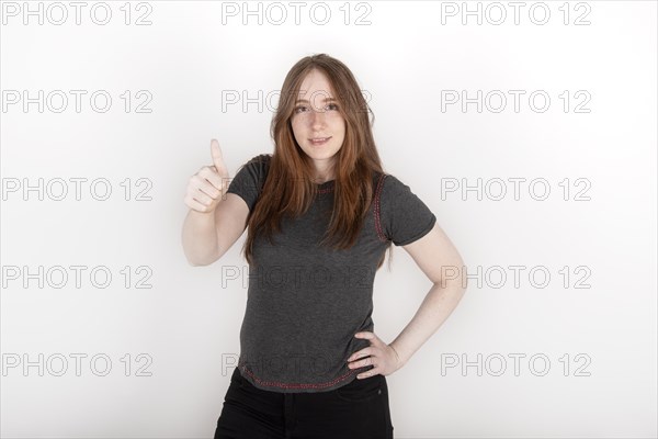 Young redhead woman looking at the camera smiling with her thumb up