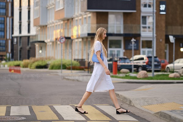 Tall woman crossing the road at a crosswalk