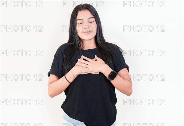 Thankful people with hands on chest. Grateful teenage girl smiling with hands on chest isolated. Positive latin girl with hands on chest