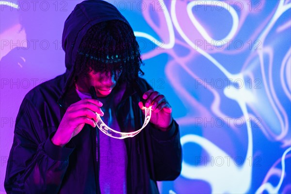 Studio portrait with purple and blue neon lights of an afro man putting on smart goggles