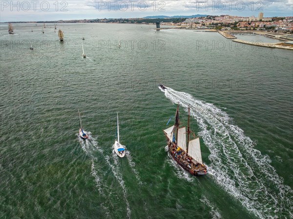 Aerial drone view of tall ships with sails sailing in Tagus river towards the Atlantic ocean in Lisbon