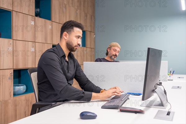 Serious man using a computer ti work in a co-working office