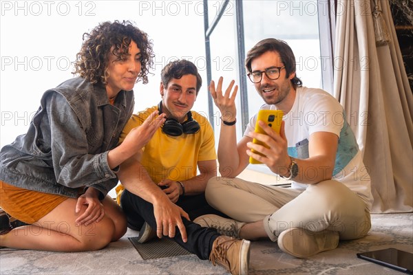 Creative business team sitting on floor working together using a mobile phone