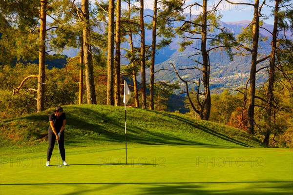 Golfer Putting on Putting Green on Golf Course Menaggio with Mountain View in Autumn in Lombardy