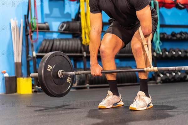 Unrecognizable handicapped man with an arm amputated weight lifting in a gym