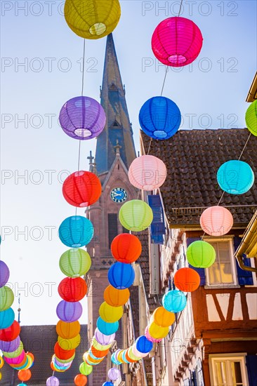 Colourful lanterns hanging in alleyway alley between half-timbered houses