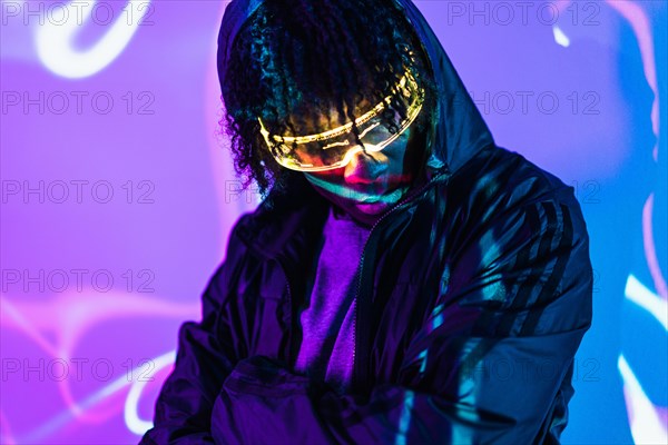 Studio portrait with purple and blue neon lights of a man in a future space using Virtual realty goggles