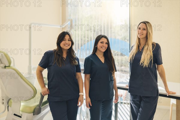 Concept of dentistry. Dental services. A team of professionals in a dental clinic. Three beautiful female dentists smile and look at camera in dental clinic