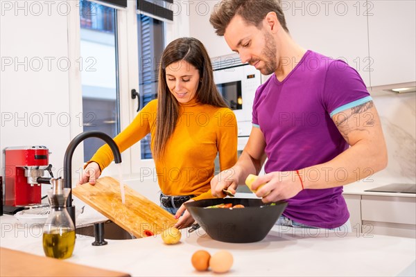 Newlywed couple cooking together in the kitchen at home