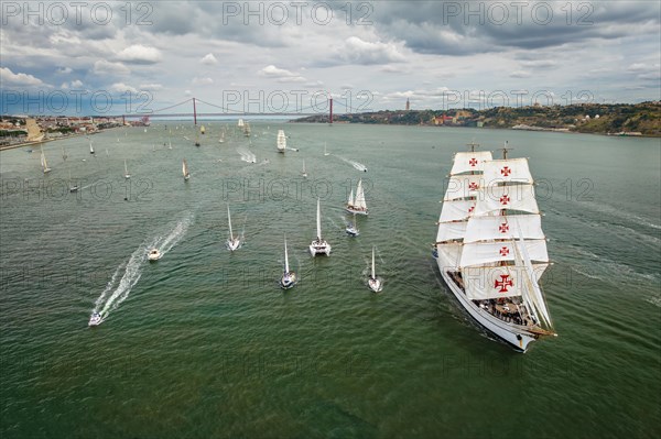 Aerial drone view of tall ships with sails sailing in Tagus river towards the Atlantic ocean in Lisbon