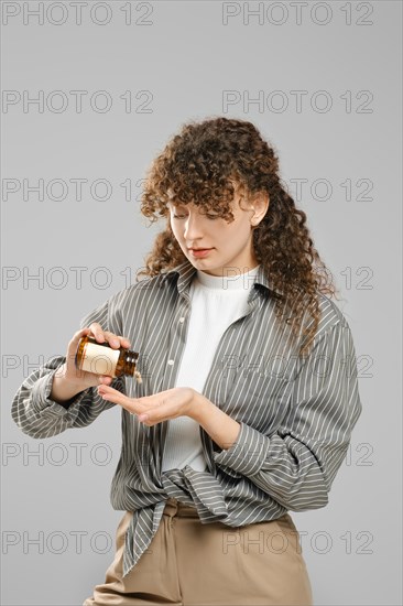 Woman shakes a vitamin pill or pill with biosupplements into her palm