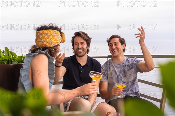 Happy friends drinking cocktails on a roof with sea views during holidays