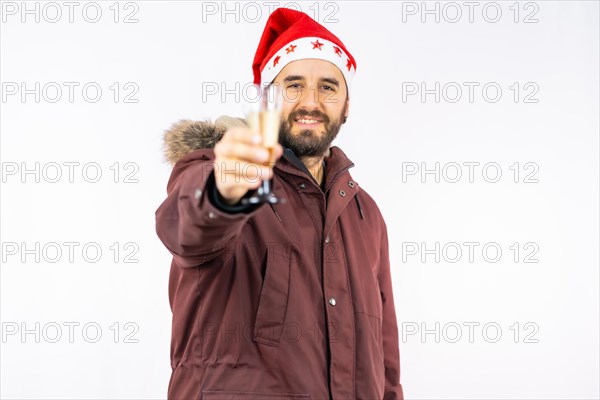 Young very happy Caucasian man with red Christmas hat toasting with a glass of champagne on a white background