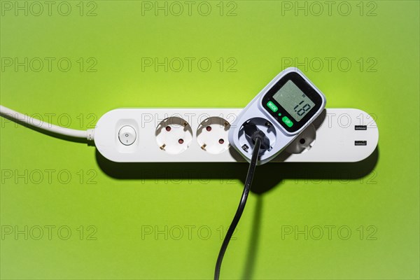 Top view of an energy cost meter in a power strip against a green background